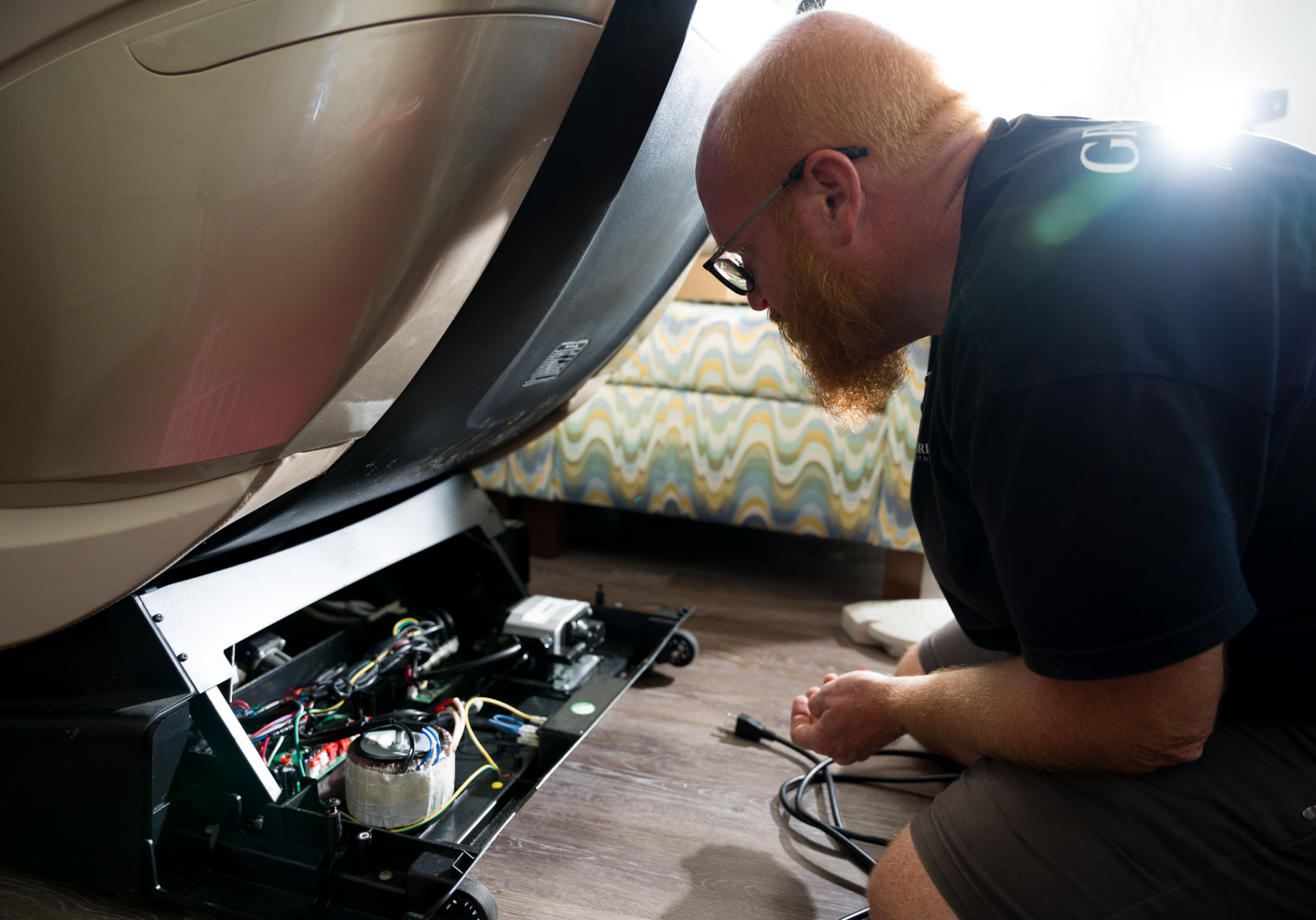 Floridian Brand USA technician repairing the internal wiring of a massage chair during in-home service.