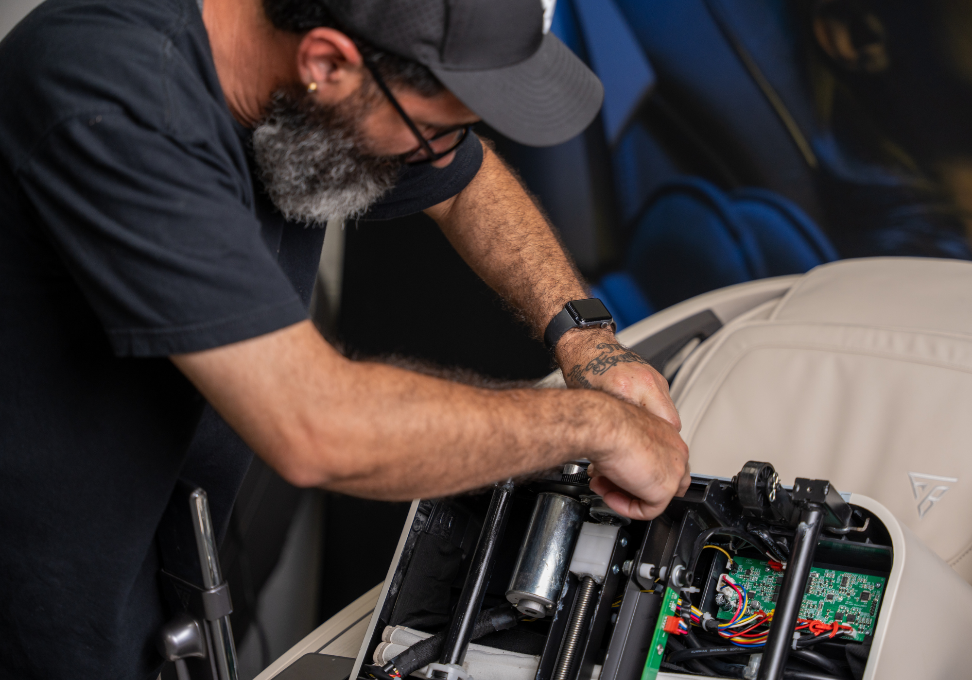Floridian Brand USA technician repairing the internal components of a massage chair with tools and circuit board exposed.