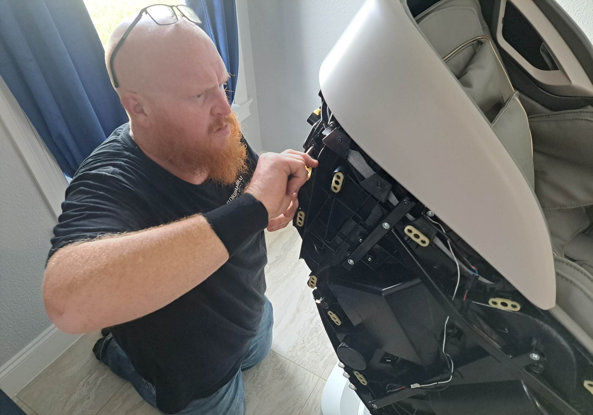 Floridian Brand USA technician performing in-home massage chair repair, inspecting internal components for warranty service.