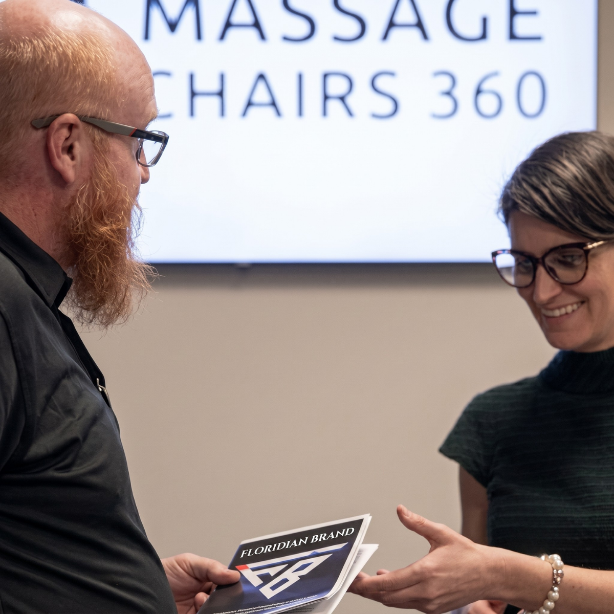 Floridian Brand ONE Partner helping customers experience massage chairs in a local showroom