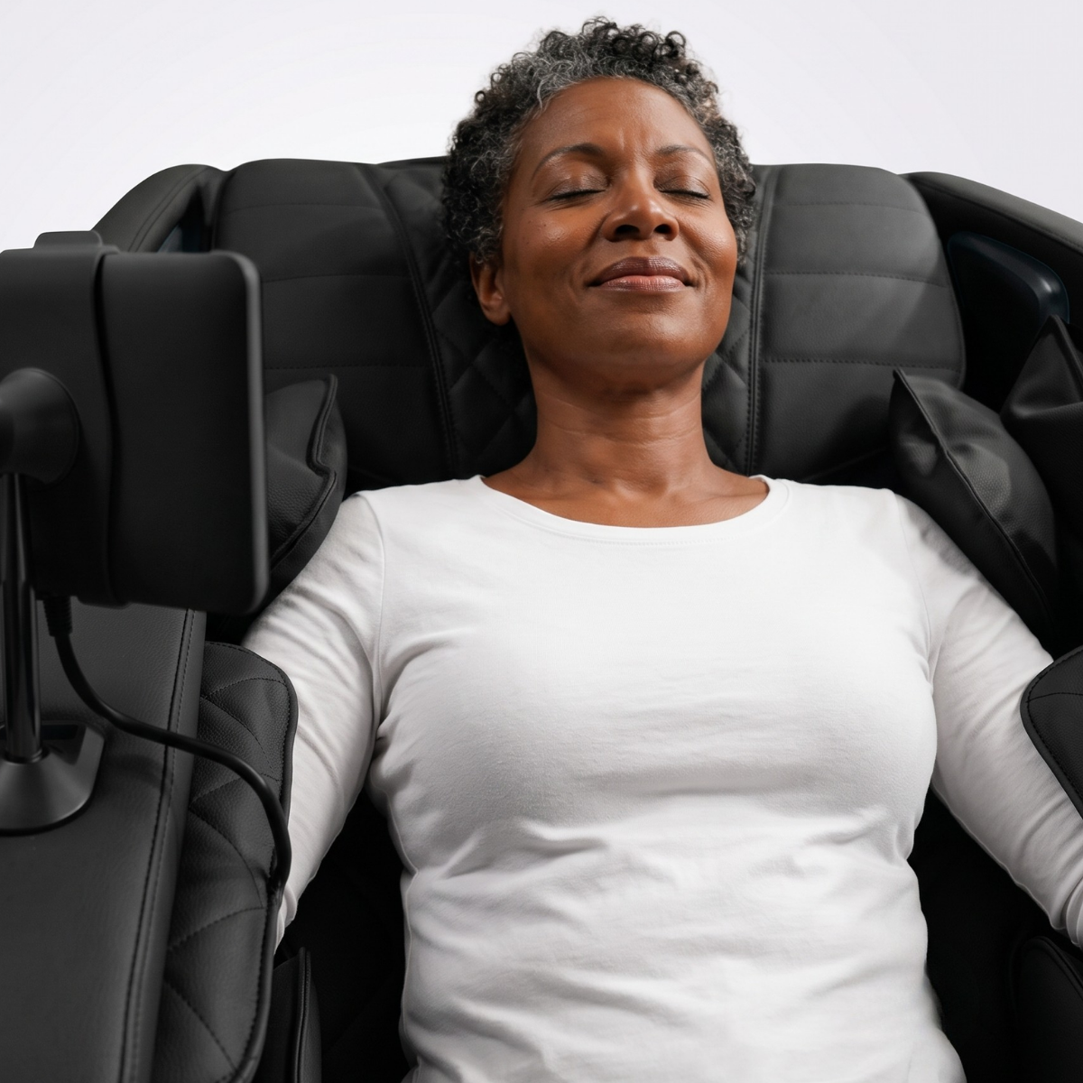 Woman relaxing in the Pioneer 6D massage chair with arms supported inside the full-body compression system.