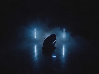 Rebel 4D massage chair in a dark cinematic studio with LED lights and reflective floor