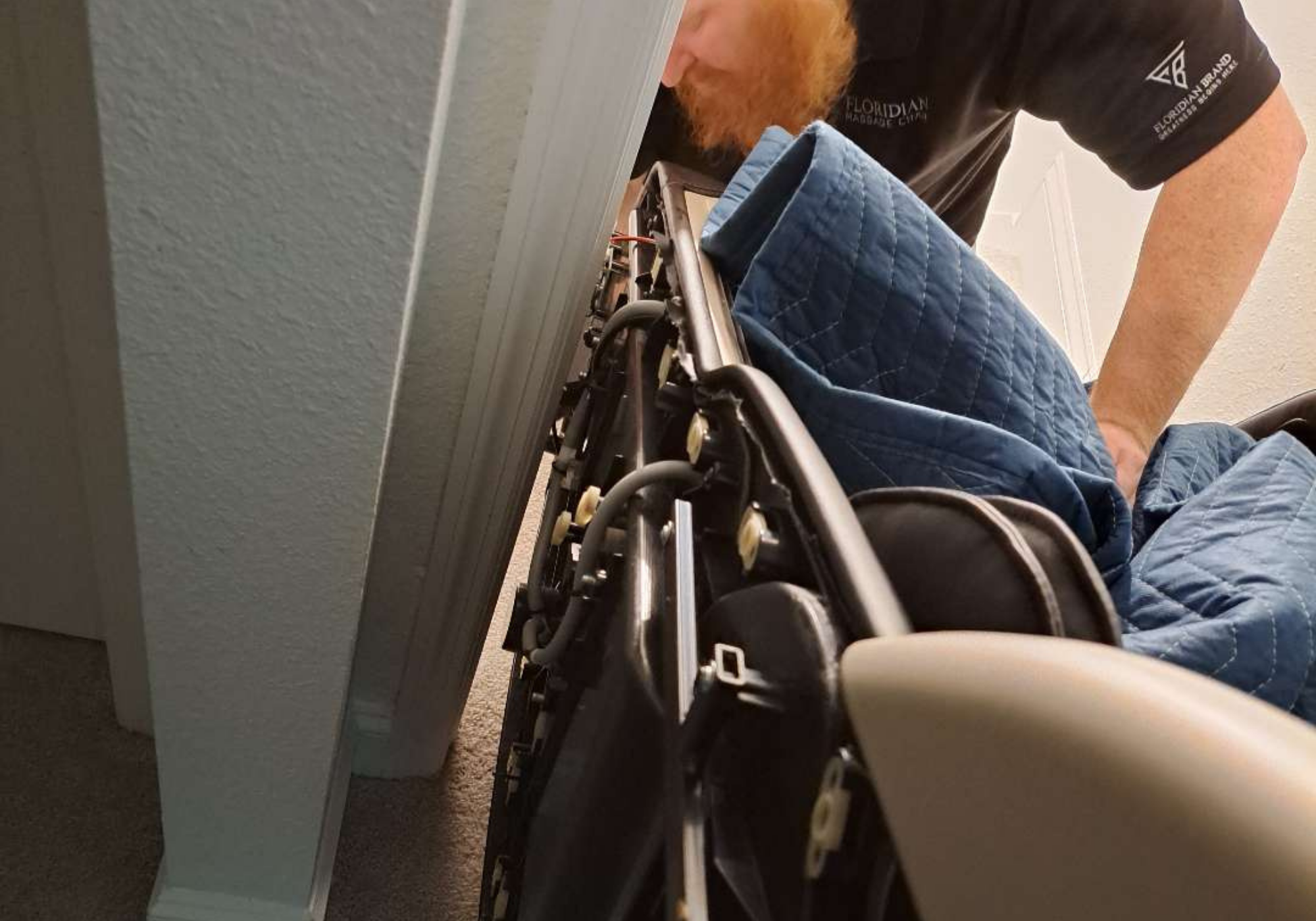 Floridian Brand technician navigating a massage chair through a narrow doorway during white-glove delivery and installation.